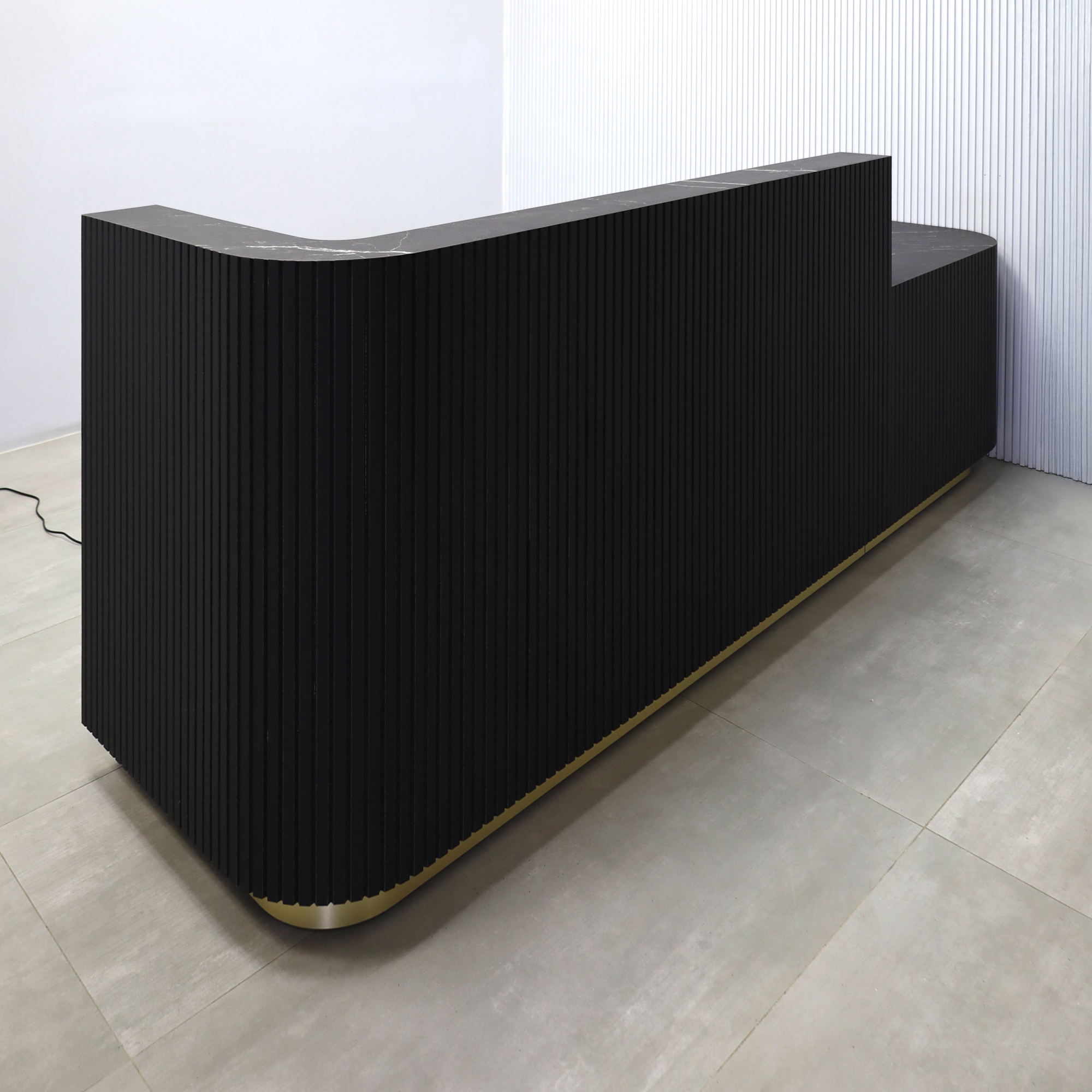 108-inch Nola ADA Reception Desk with Black traceless laminate tambour counter & desk, Black Stone Palazzo laminate workspace, gold aluminum toe-kick, warm white LED. 