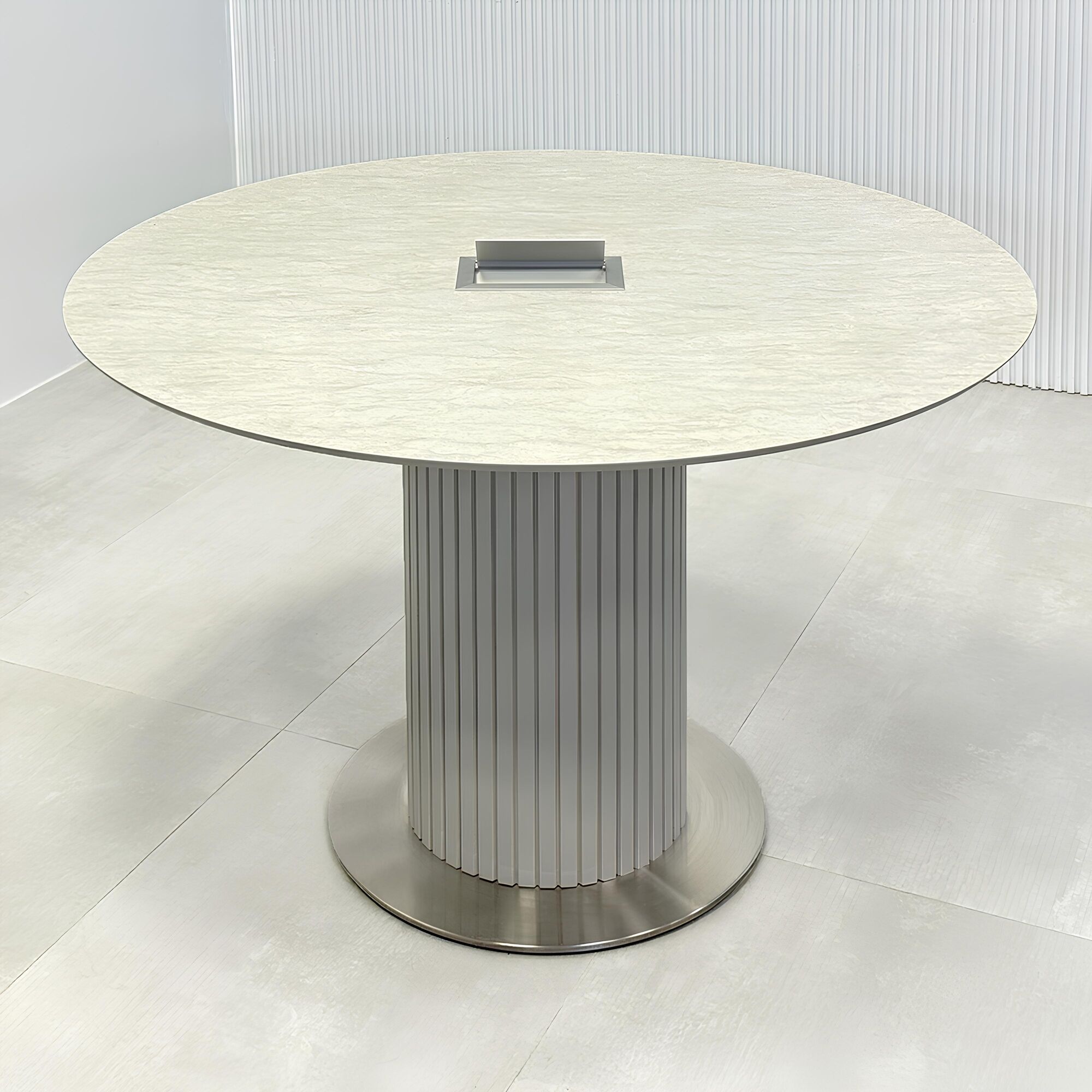 47-inch Aurora Round Conference Table with spanish limestone engineered surface top, fog gray tambour pedestal base, brushed stainless steel base, and Mx3 power box in silver.