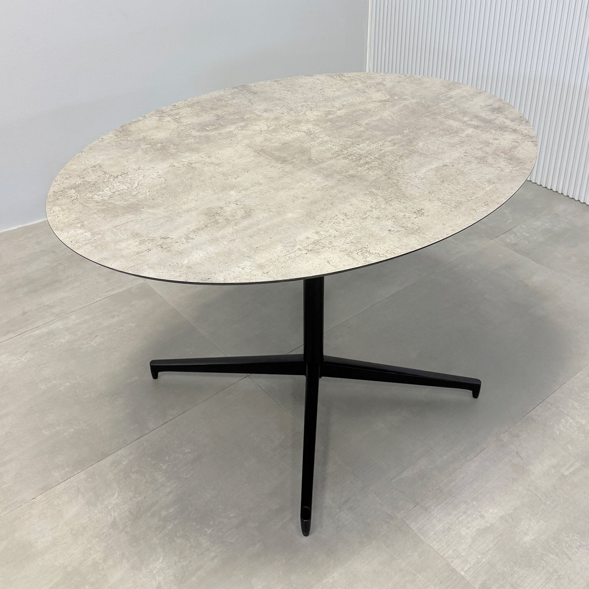 52-inch Aurora Dining Table with Star Base in 1/2 industrial concrete engineered surface top, and star base in black.