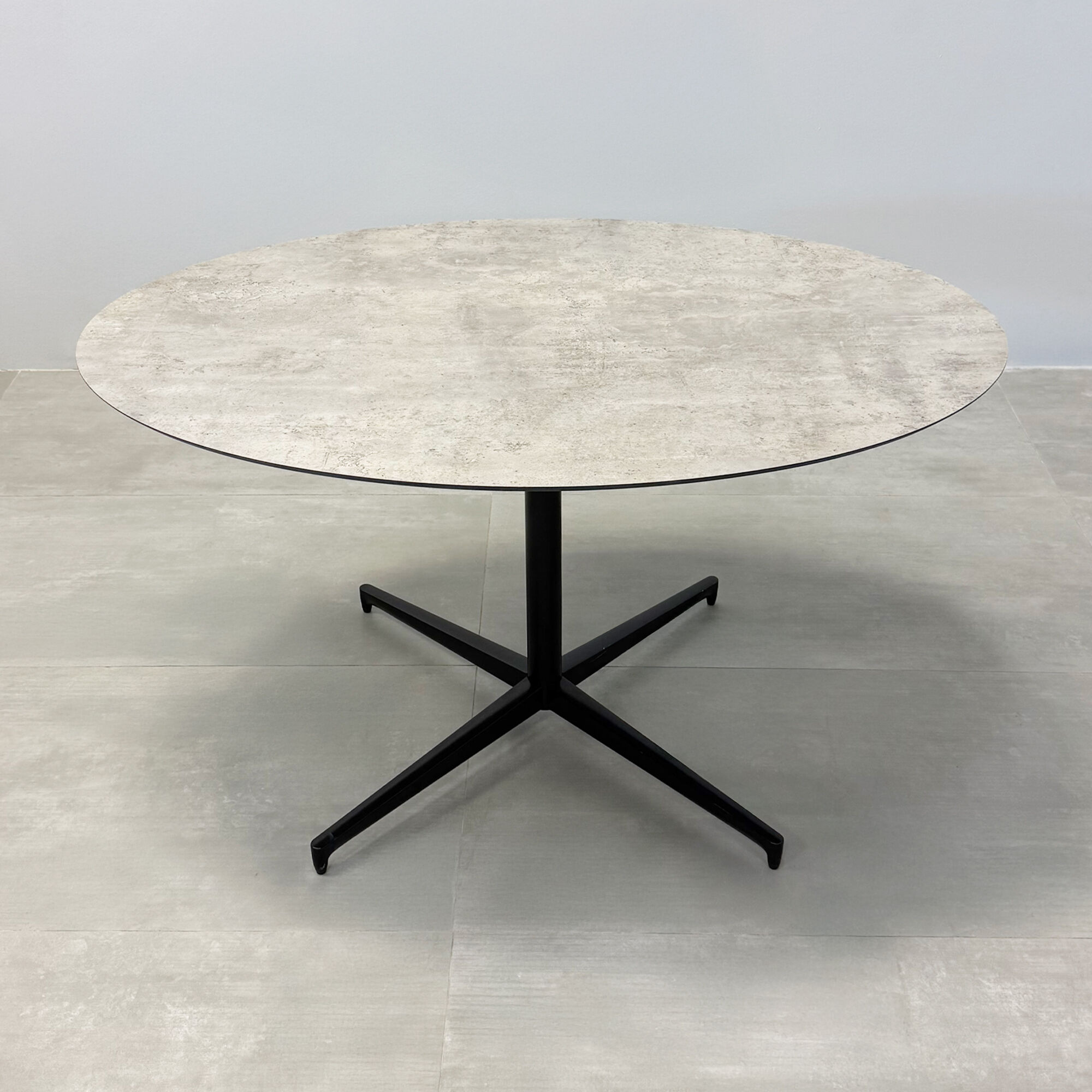 52-inch Aurora Dining Table with Star Base in 1/2 industrial concrete engineered surface top, and star base in black.