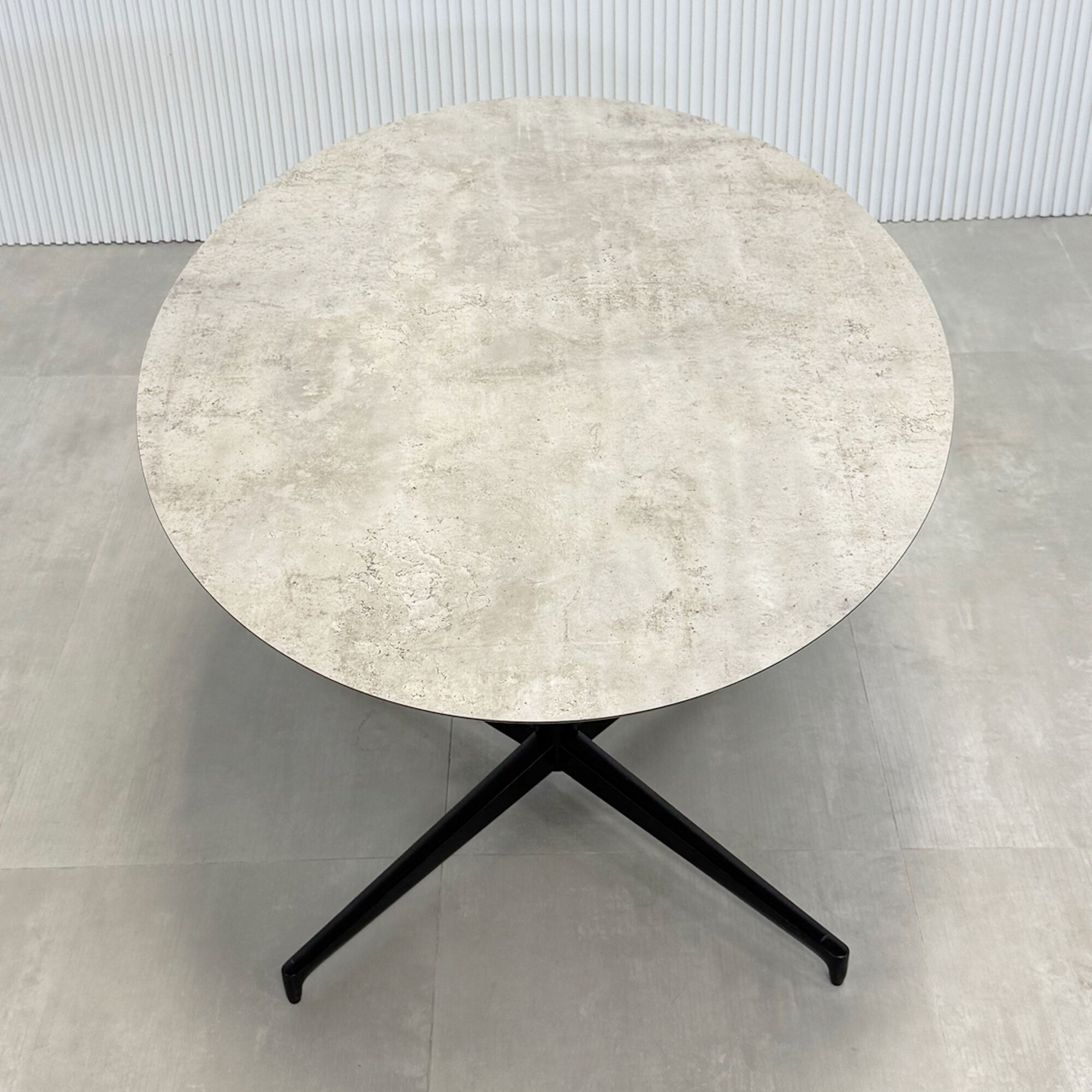 52-inch Aurora Dining Table with Star Base in 1/2 industrial concrete engineered surface top, and star base in black.