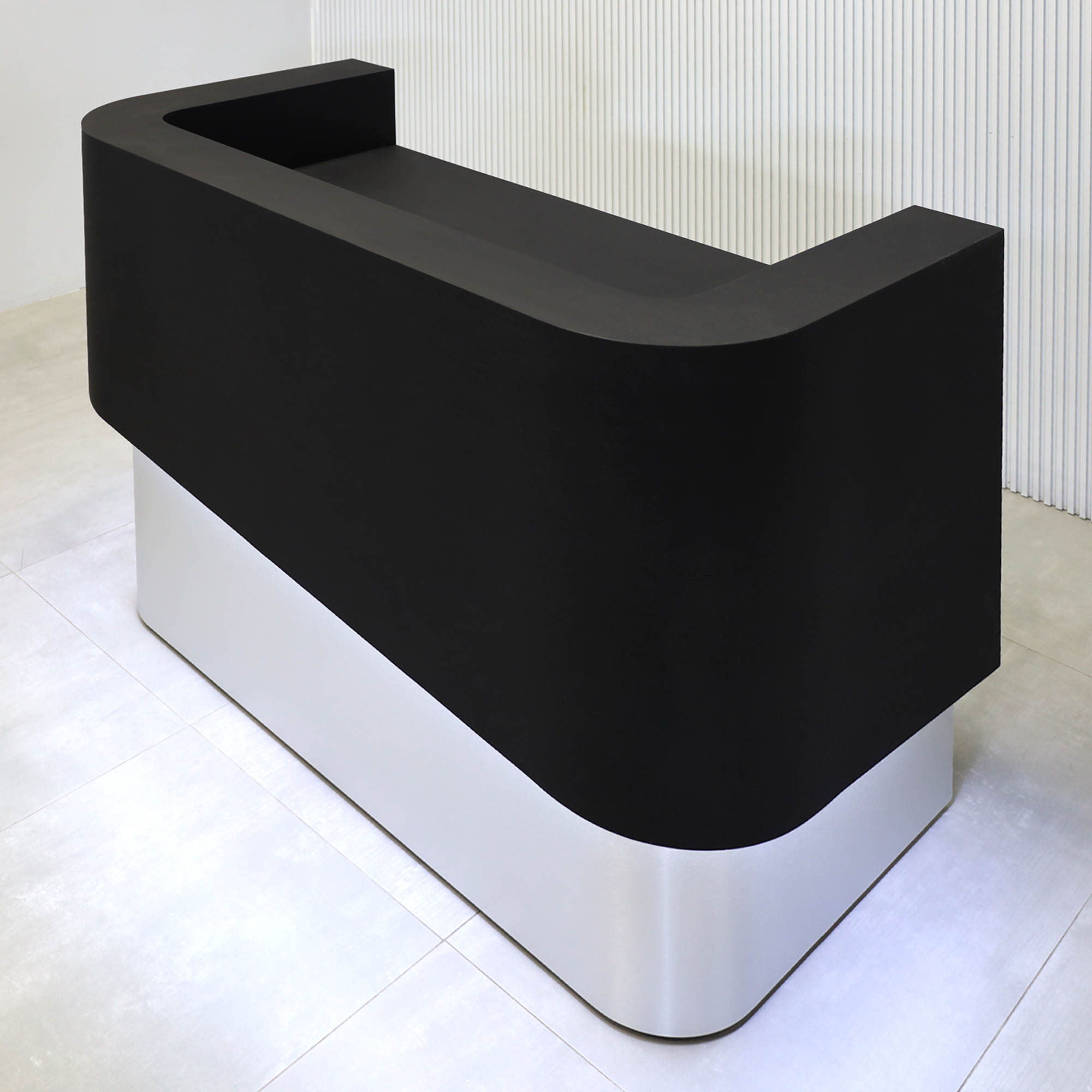 60-inch Nola Curved Custom Reception Desk with Black Cider matte laminate workspace and counter. Base in Brushed Aluminum finish and White LED.