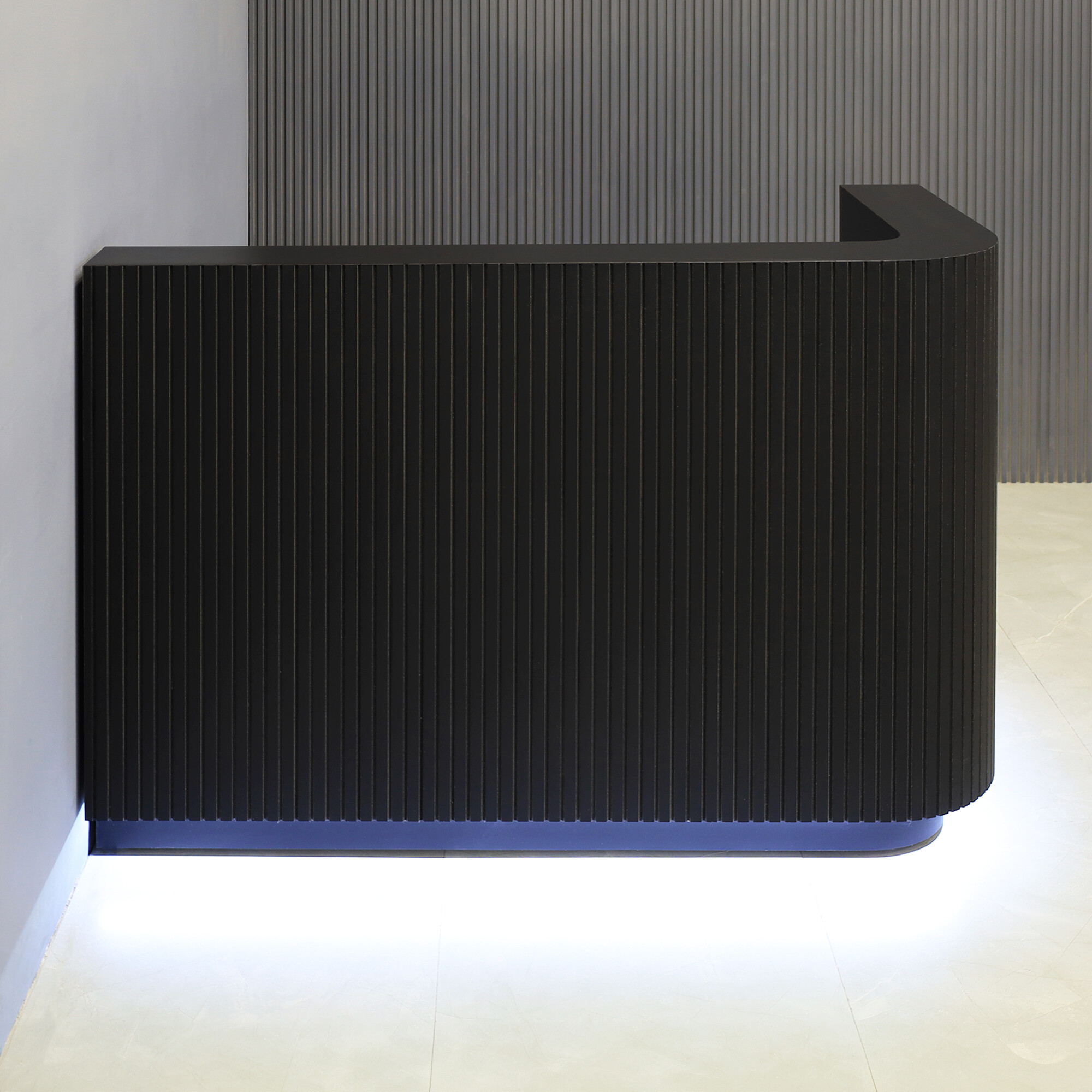 60-inch Nola L-Shape Reception Desk in black traceless tambour main desk, black matte laminate workspace, black traceless laminate toe-kick, and warm white LED.