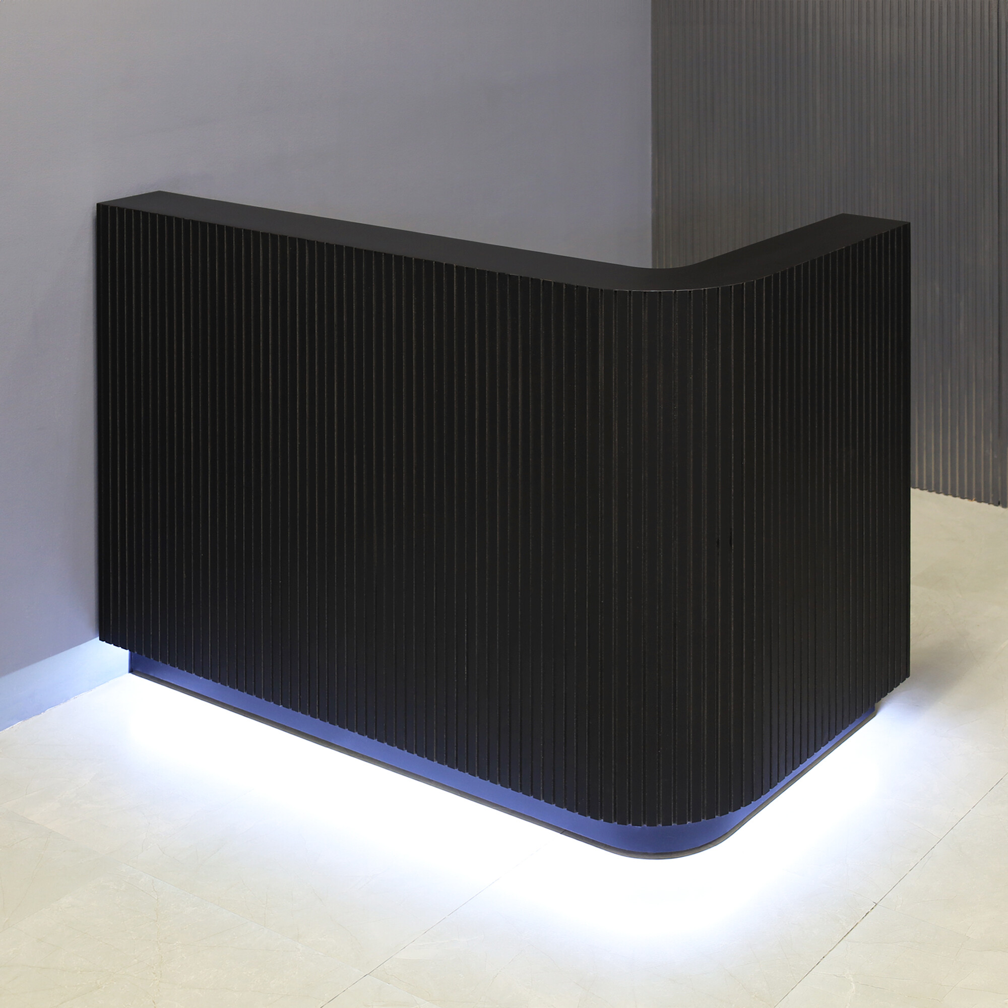 60-inch Nola L-Shape Reception Desk in black traceless tambour main desk, black matte laminate workspace, black traceless laminate toe-kick, and warm white LED.