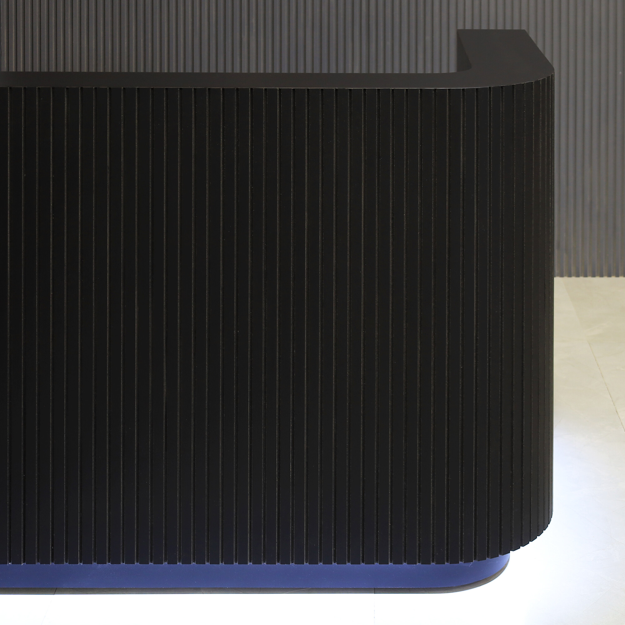 60-inch Nola L-Shape Reception Desk in black traceless tambour main desk, black matte laminate workspace, black traceless laminate toe-kick, and warm white LED.