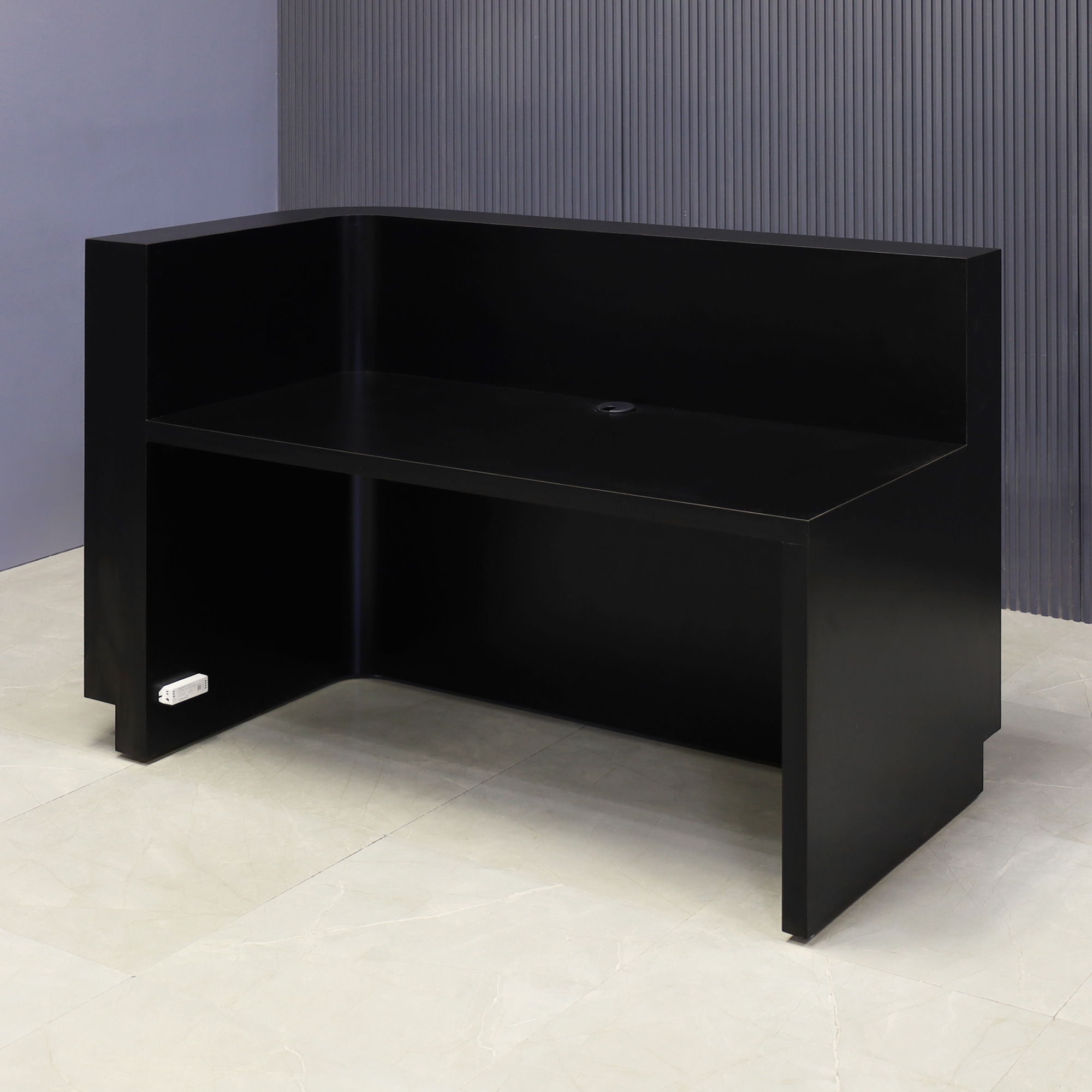 60-inch Nola L-Shape Reception Desk in black traceless tambour main desk, black matte laminate workspace, black traceless laminate toe-kick, and warm white LED.