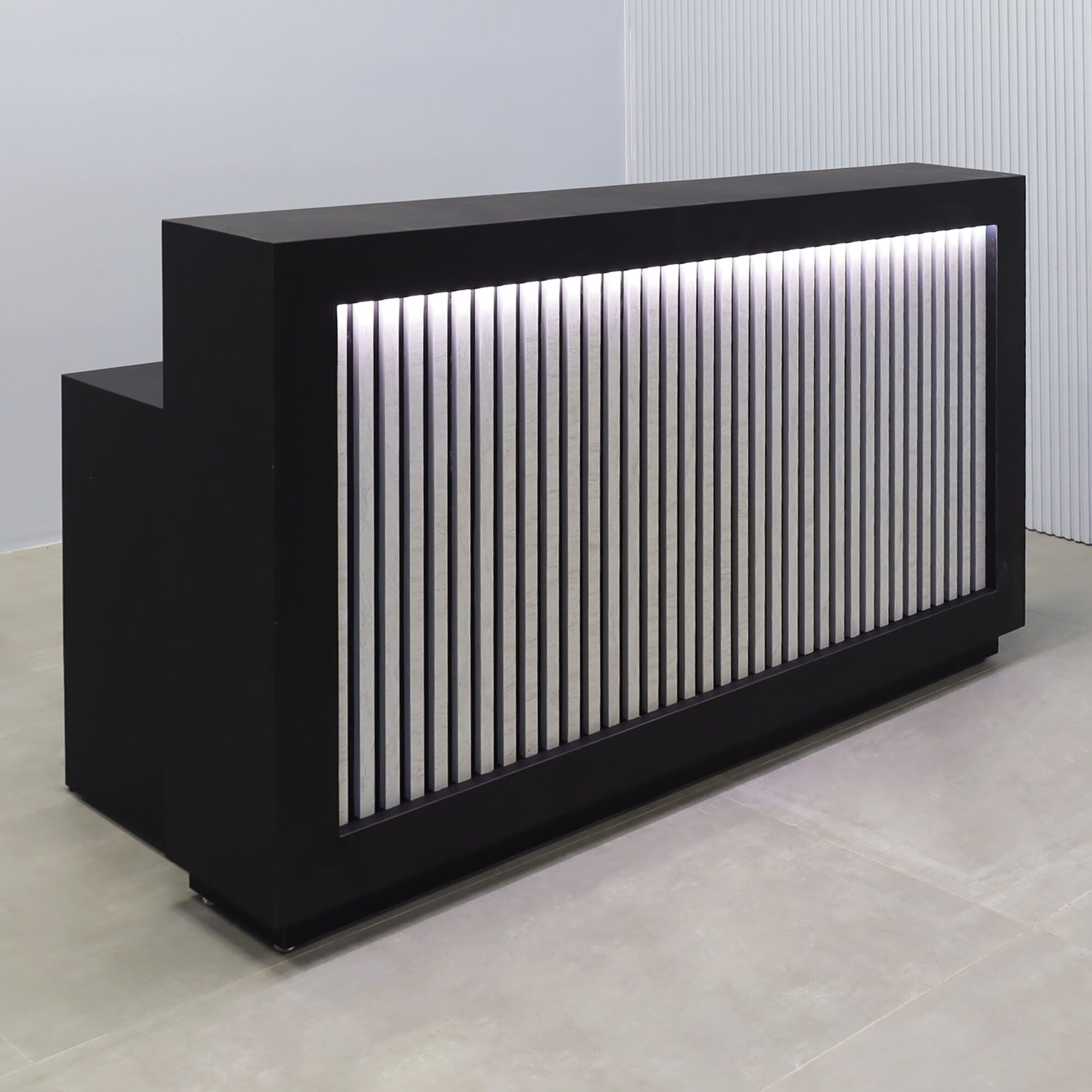 72-inch Vegas Designer Reception Desk in black traceless laminate main desk, spanish limestone engineered surface slats front panel, and warm white LED.