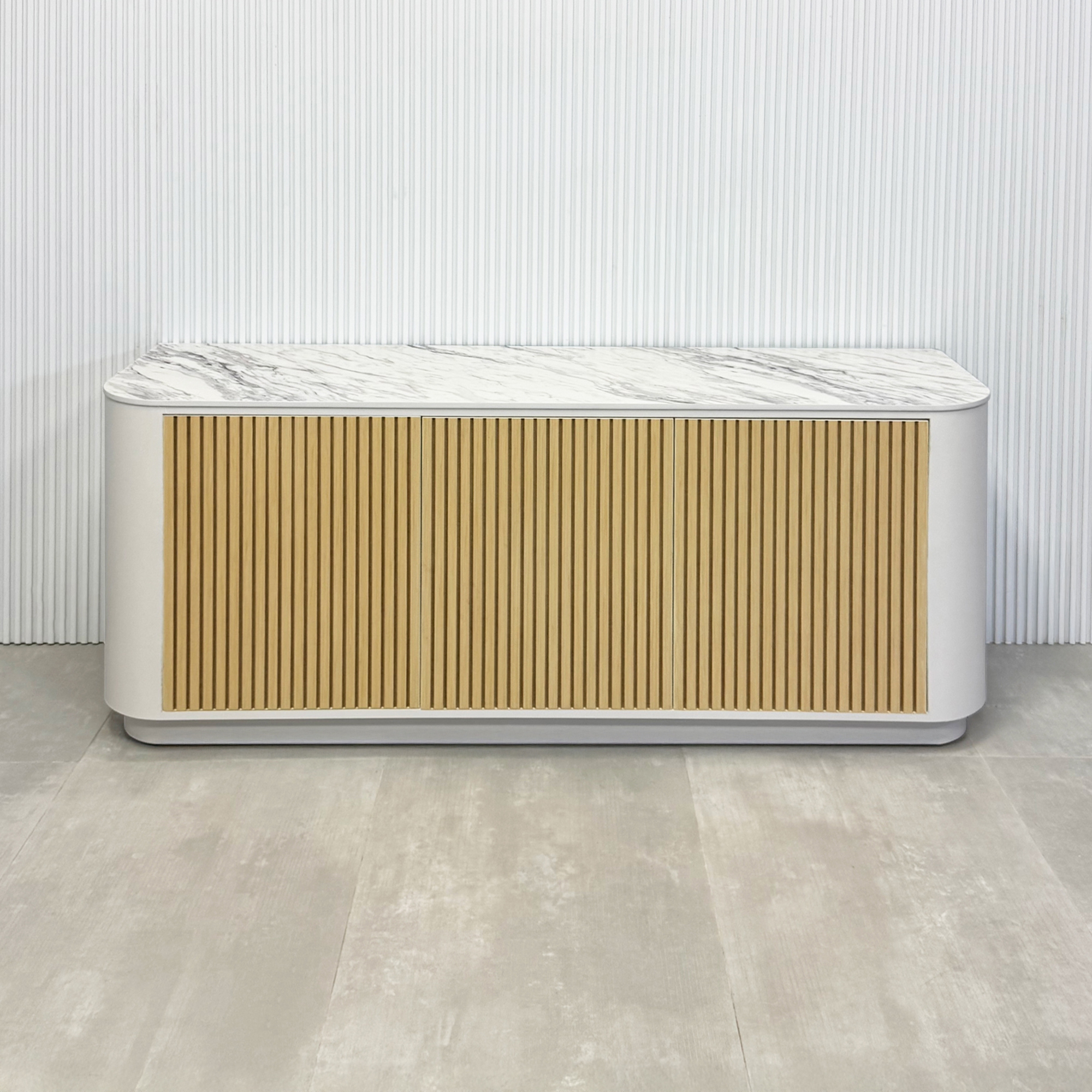 72-inch Florence Storage Credenza with 1/2 Calcutta engineered surface top, dover off white laminate credenza inside, and maple tambour front doors.