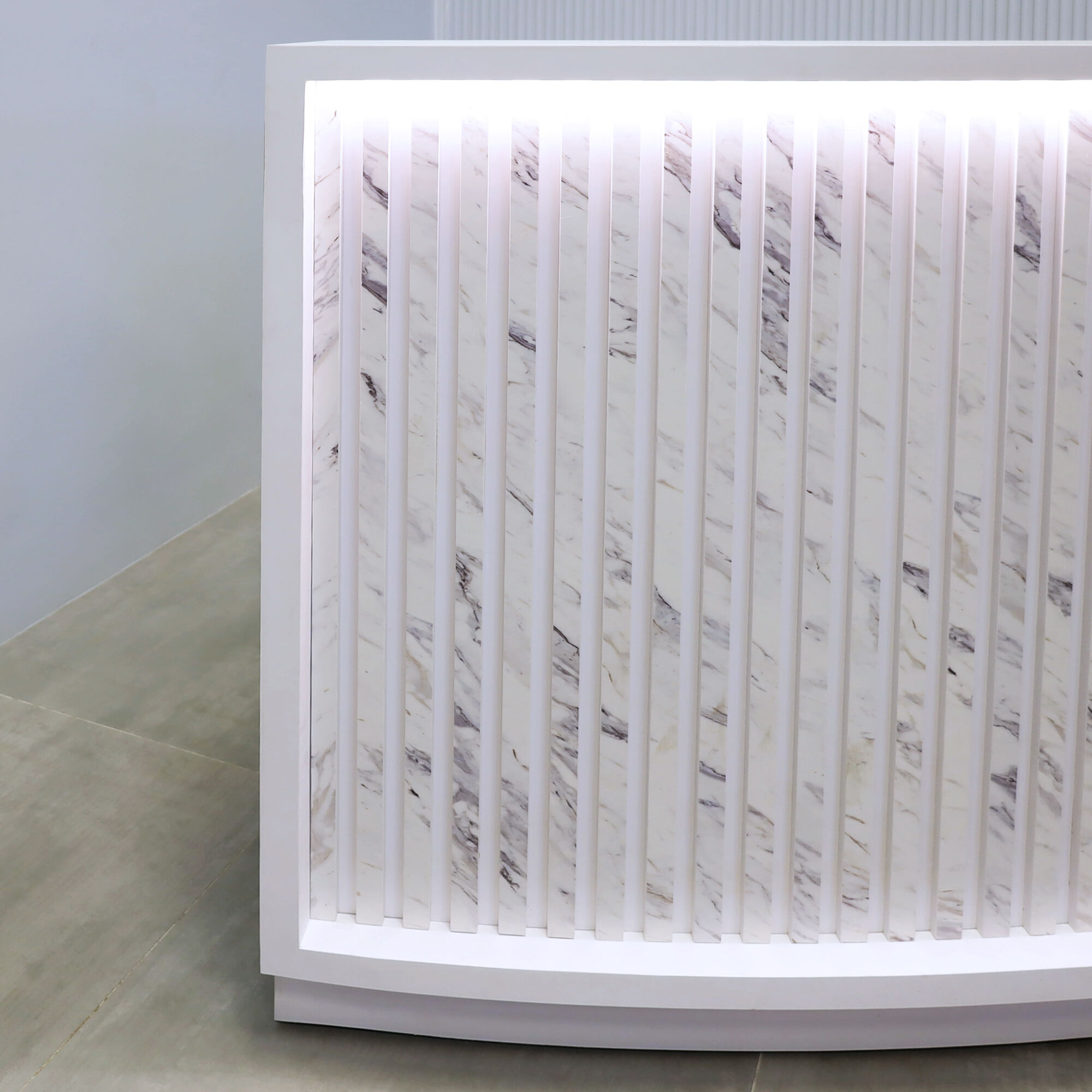 72-inch Seattle X2 Reception Desk in white matte PVC main desk, calcutta blanc engineered surface slats curved front panel, and warm white LED.