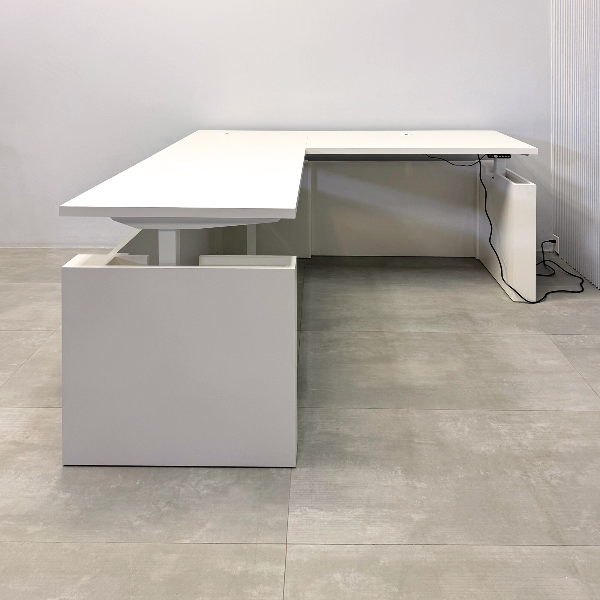 80-inch Denver L-Shape Laminate Executive Desk with Sit-Stand Mechanism with Dover Off-White matte laminate top and base. Washed Oak tambour privacy panel and white base.