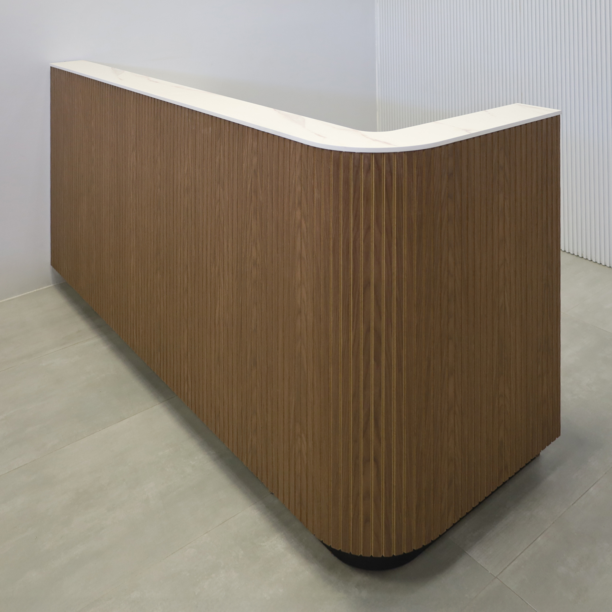 84-inch Nola L Shape Reception Desk with Walnut Tambour front, Solenne Marble engineered surface top, and black matte laminate toe-kick.