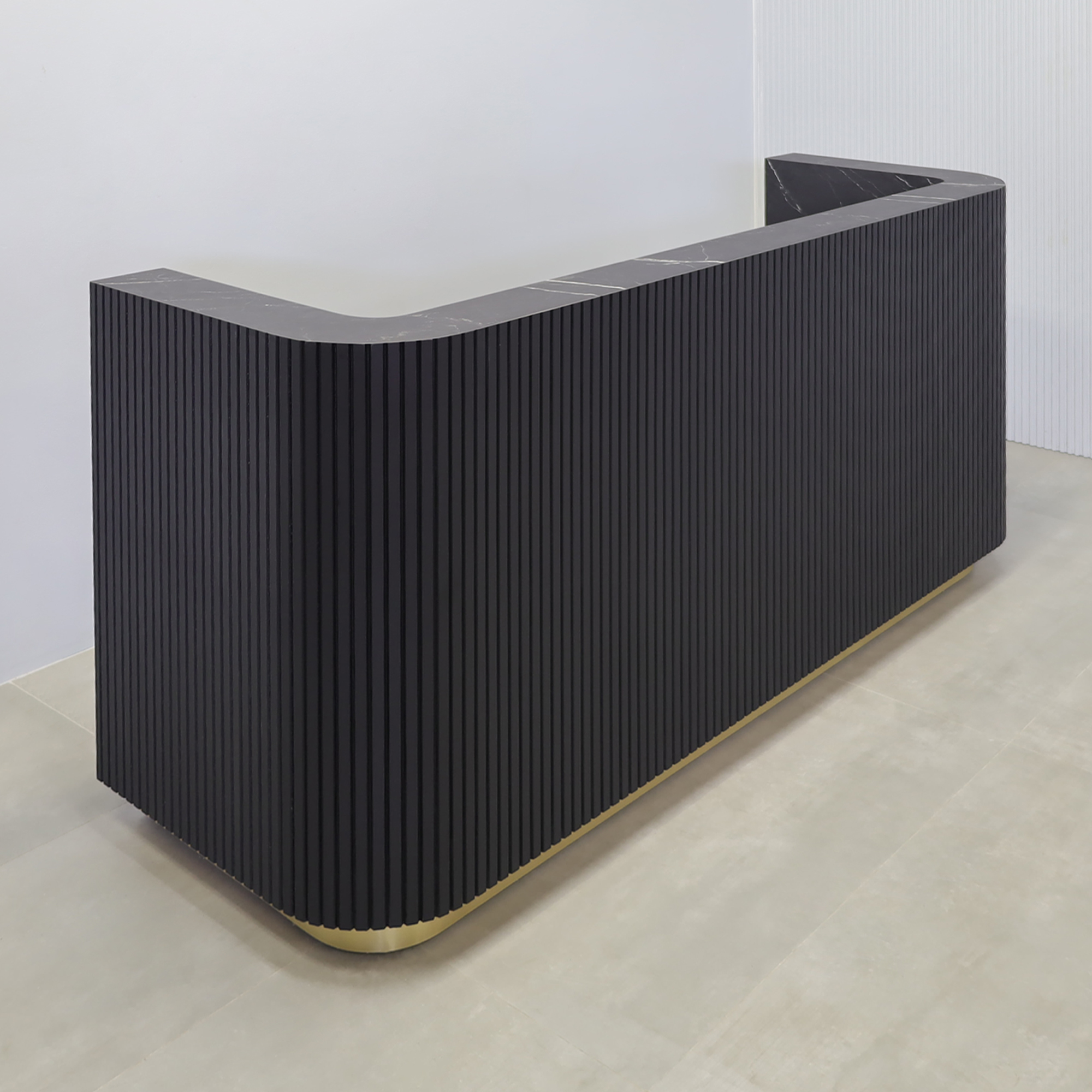 90-inch  Nola Custom Reception Desk with Black Traceless Tambour main desk, and Black Stone PVC laminate workspace. Gold aluminum toe-kick, and warm white LED. 