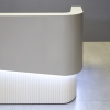60-inch Nola Curved Reception Desk in folkstone gray matte laminate counter & inside desk, white tambour outside desk, with warm white LED, shown here.
